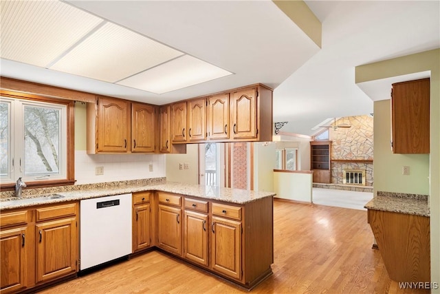 kitchen with a fireplace, kitchen peninsula, sink, white dishwasher, and light hardwood / wood-style flooring