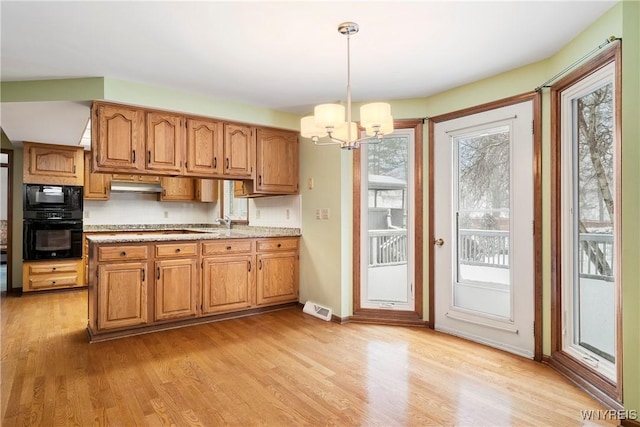 kitchen with black appliances, a notable chandelier, a wealth of natural light, and hanging light fixtures