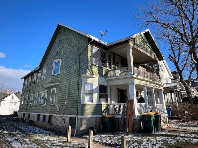 snow covered property with a balcony and a porch