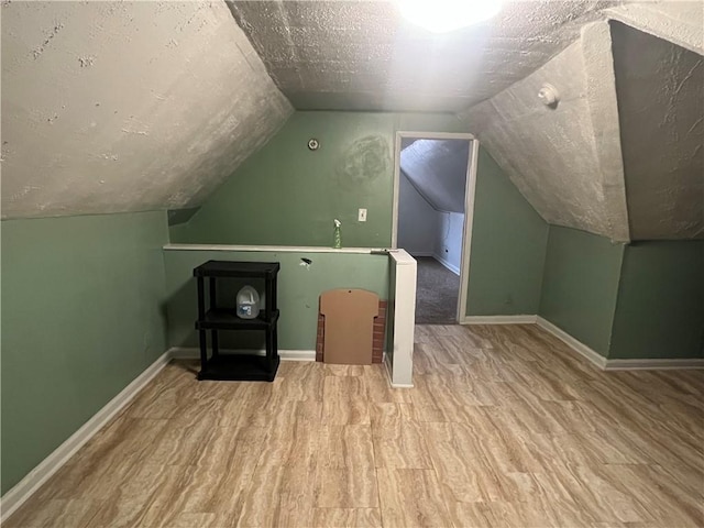 bonus room with a textured ceiling and vaulted ceiling