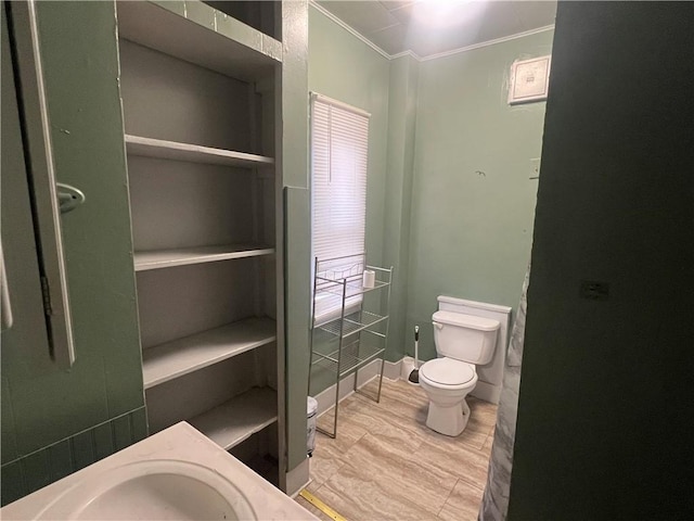 bathroom with toilet, crown molding, wood-type flooring, and sink