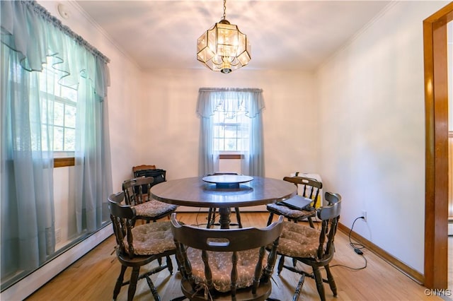 dining space with a baseboard radiator, a wealth of natural light, light hardwood / wood-style floors, and a notable chandelier