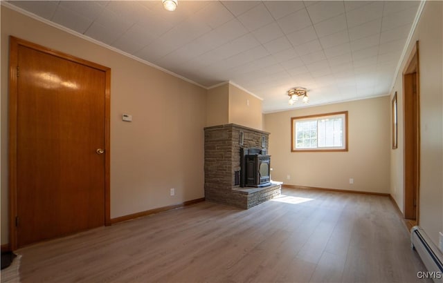 unfurnished living room featuring a baseboard heating unit, ornamental molding, a wood stove, and light hardwood / wood-style flooring