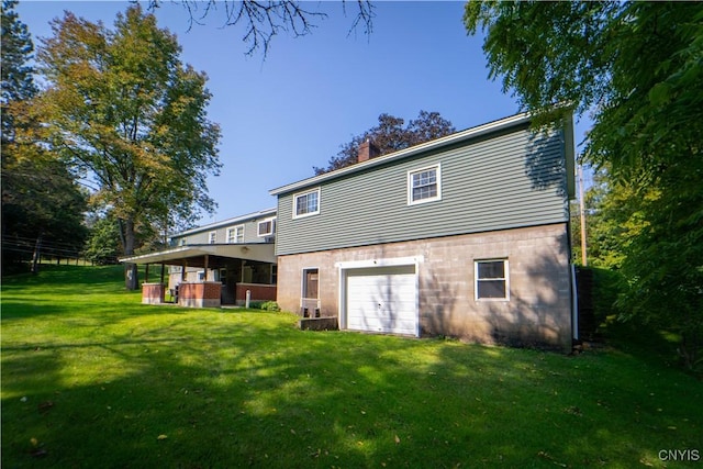 rear view of property with a garage and a lawn