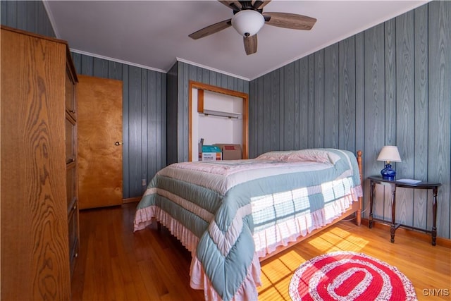 bedroom with wood walls, ceiling fan, hardwood / wood-style flooring, and crown molding