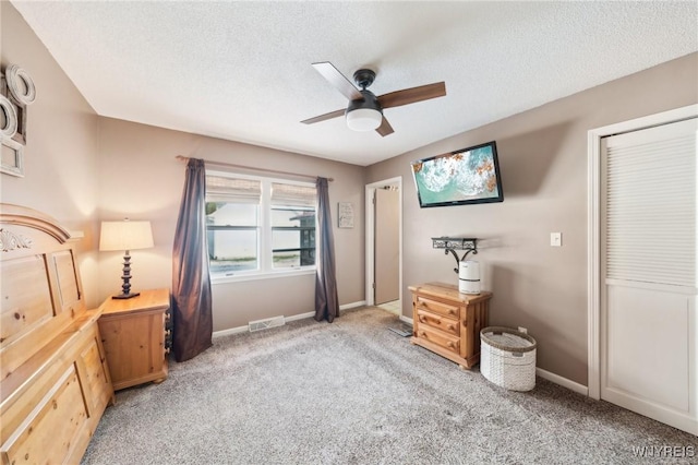 bedroom with a textured ceiling, ceiling fan, and light colored carpet