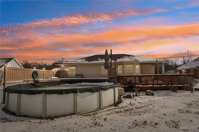 back house at dusk featuring a pool side deck