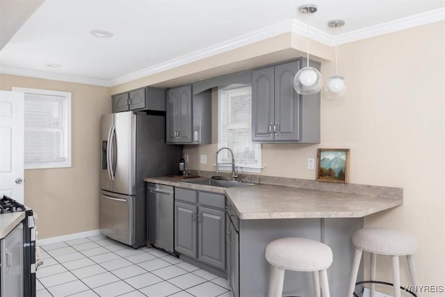 kitchen featuring stainless steel appliances, gray cabinetry, hanging light fixtures, and sink