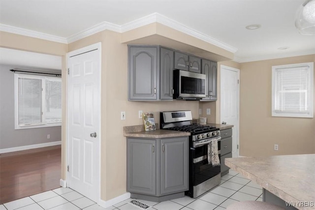 kitchen with gray cabinets, light tile patterned floors, crown molding, and appliances with stainless steel finishes