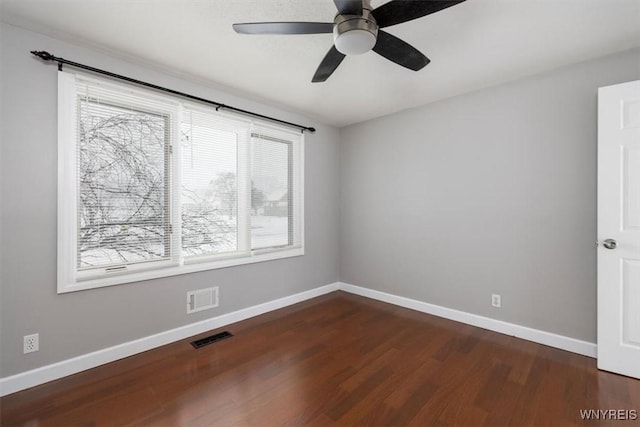 empty room featuring ceiling fan, dark wood-type flooring, and plenty of natural light