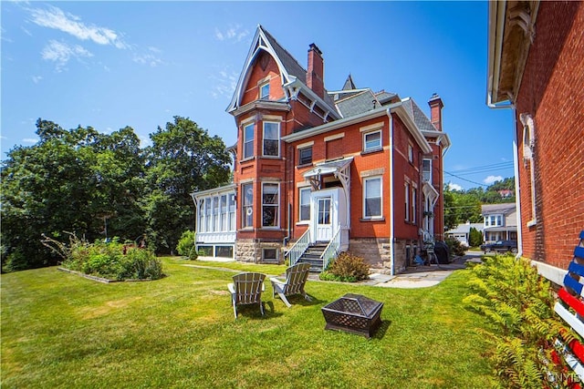 rear view of house with an outdoor fire pit and a yard