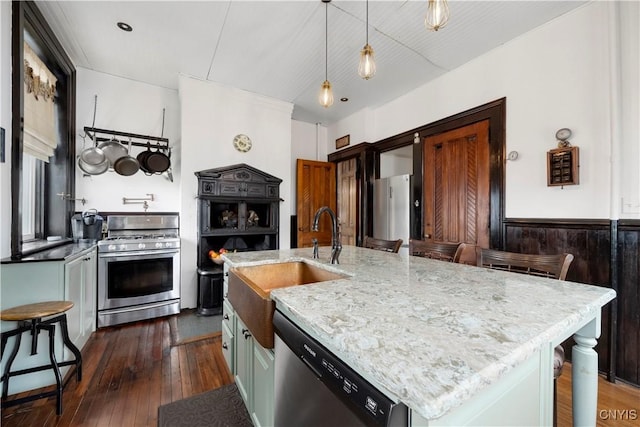 kitchen featuring appliances with stainless steel finishes, an island with sink, a kitchen bar, sink, and decorative light fixtures