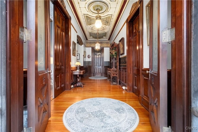 hallway with ornamental molding, light hardwood / wood-style floors, and a tray ceiling