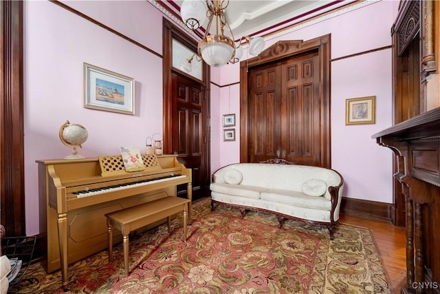 living area with an inviting chandelier, ornamental molding, and light hardwood / wood-style floors