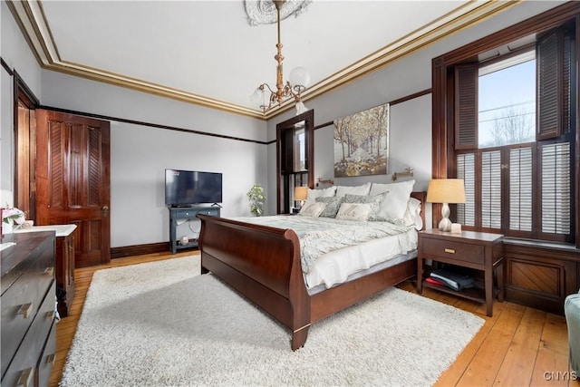 bedroom with a chandelier, ornamental molding, and light hardwood / wood-style flooring