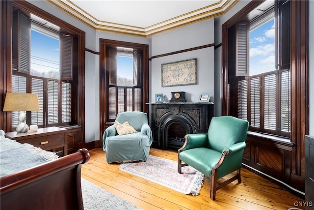 sitting room featuring wood-type flooring, a fireplace, and crown molding