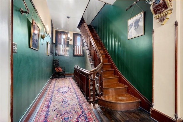 stairway with a notable chandelier and wood-type flooring