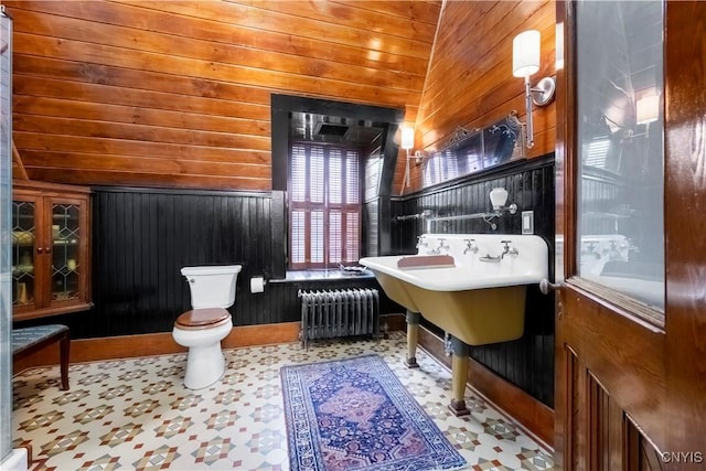 bathroom featuring toilet, wood walls, and radiator heating unit