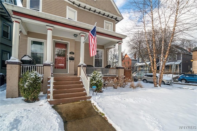 snow covered property entrance featuring a porch