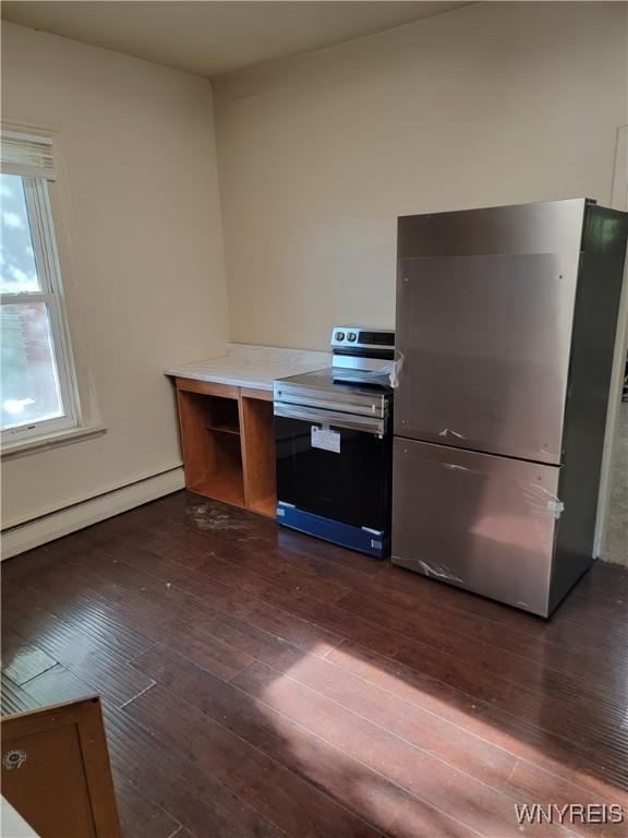 kitchen with dark wood-type flooring, baseboard heating, and appliances with stainless steel finishes