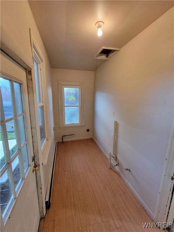 laundry room with baseboard heating and light wood-type flooring