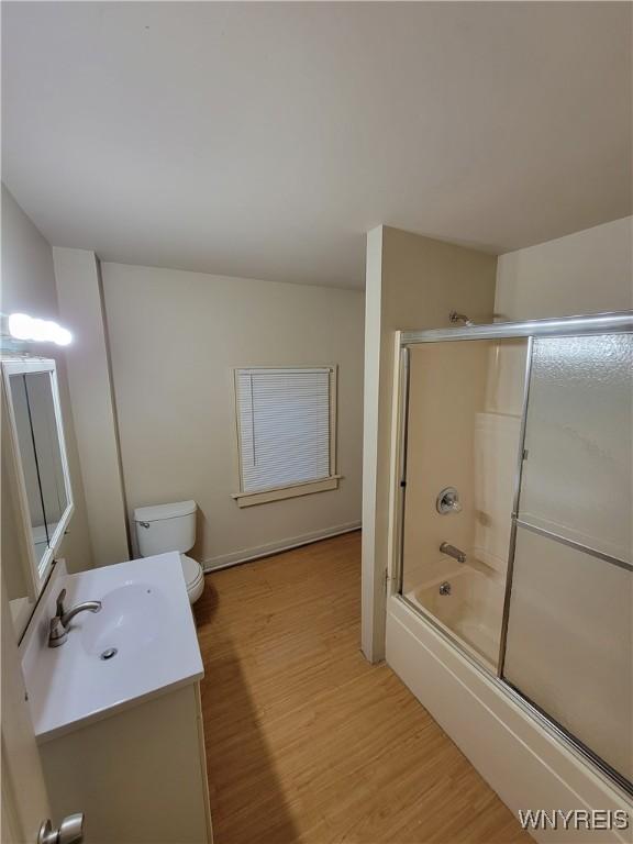 full bathroom with toilet, bath / shower combo with glass door, vanity, and hardwood / wood-style floors