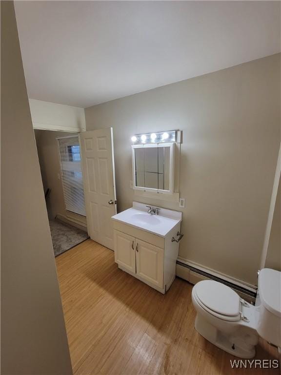 bathroom featuring hardwood / wood-style floors, a baseboard radiator, vanity, and toilet