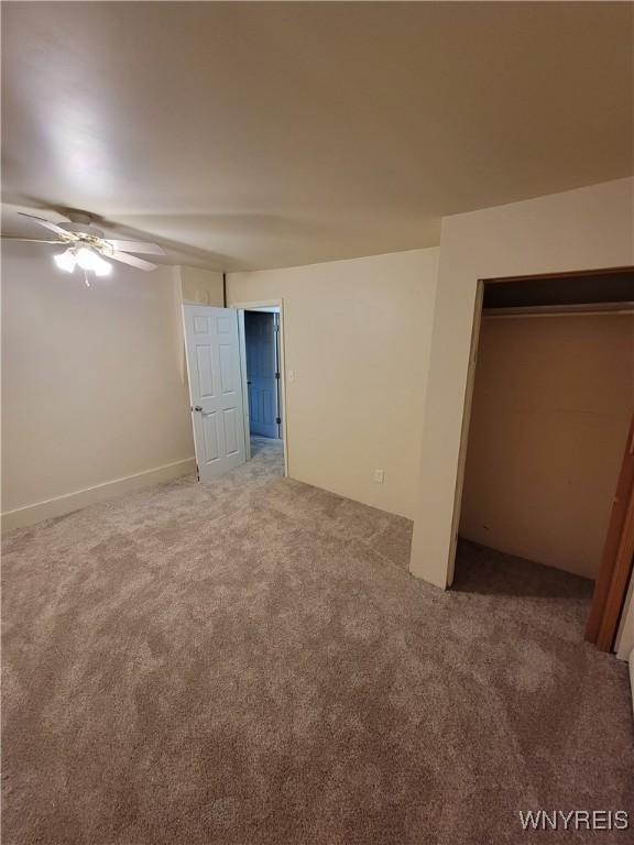 unfurnished bedroom featuring ceiling fan, a closet, and carpet flooring