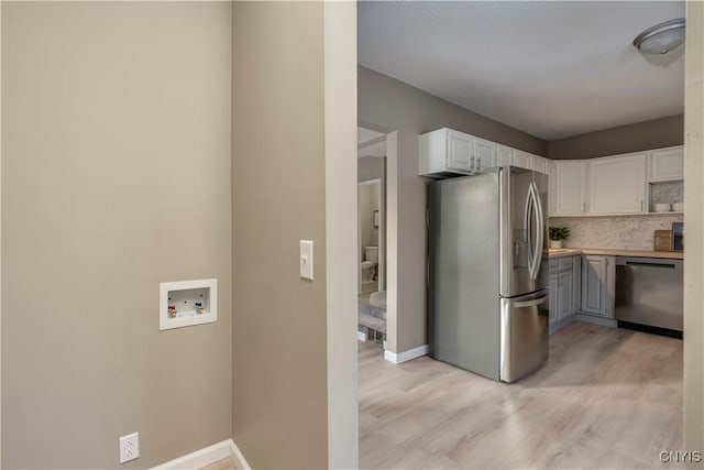 kitchen featuring stainless steel appliances, light hardwood / wood-style floors, white cabinets, and tasteful backsplash