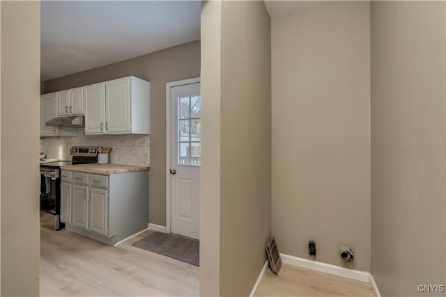 kitchen featuring light wood-type flooring, electric stove, tasteful backsplash, and white cabinetry