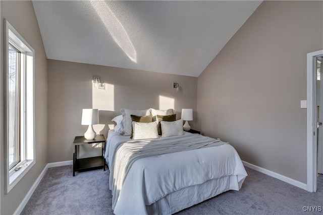 bedroom with lofted ceiling, a textured ceiling, and light carpet