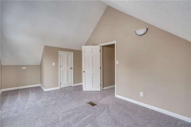 bonus room with a textured ceiling, light carpet, and lofted ceiling