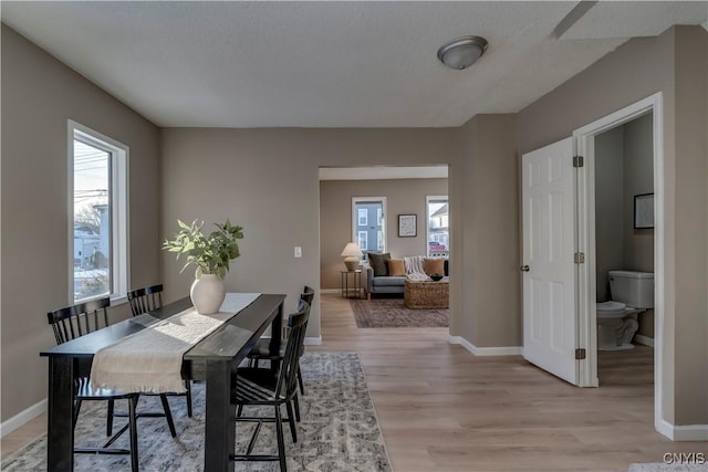 dining space with light wood-type flooring and a textured ceiling