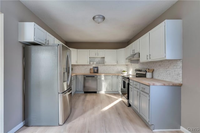 kitchen with appliances with stainless steel finishes, light hardwood / wood-style floors, white cabinets, backsplash, and butcher block counters