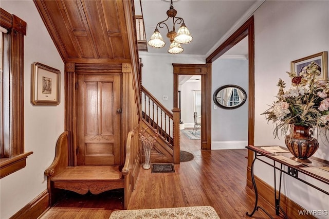 foyer with dark wood-type flooring, a notable chandelier, and ornamental molding