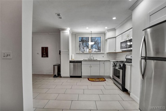 kitchen with sink, white cabinets, ornamental molding, tasteful backsplash, and appliances with stainless steel finishes