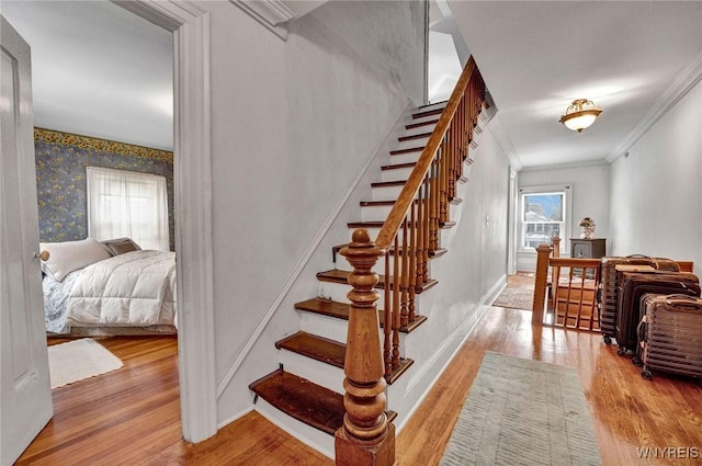 stairs featuring crown molding and hardwood / wood-style flooring