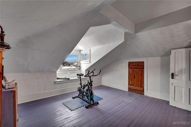 workout room featuring dark wood-type flooring and vaulted ceiling