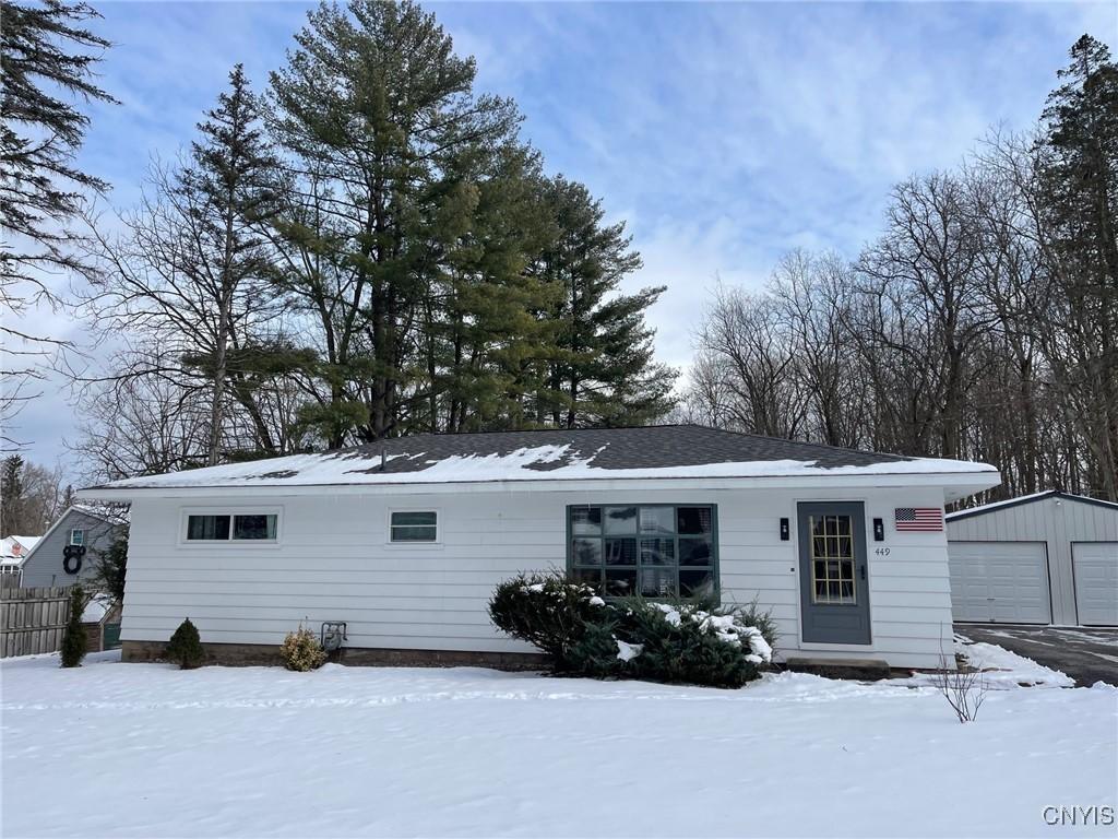 snow covered rear of property with a garage and an outbuilding