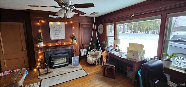 living area with a fireplace, ceiling fan, and light wood-type flooring