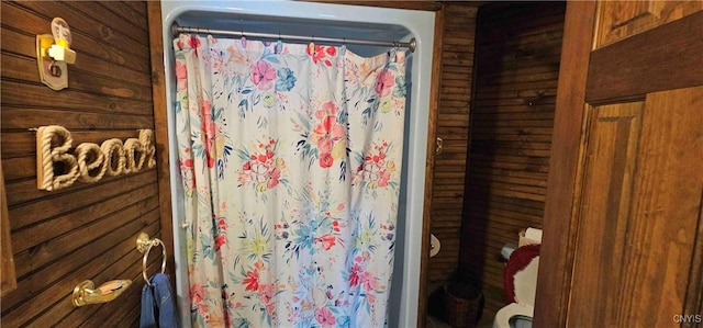 bathroom featuring curtained shower and wood walls