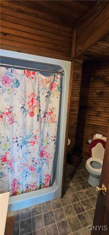 bathroom featuring a shower with shower curtain, wooden walls, and toilet