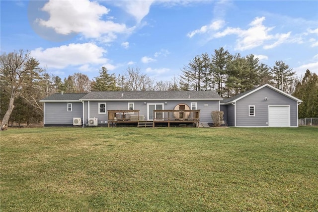 rear view of property featuring a deck, a yard, an outbuilding, and a garage