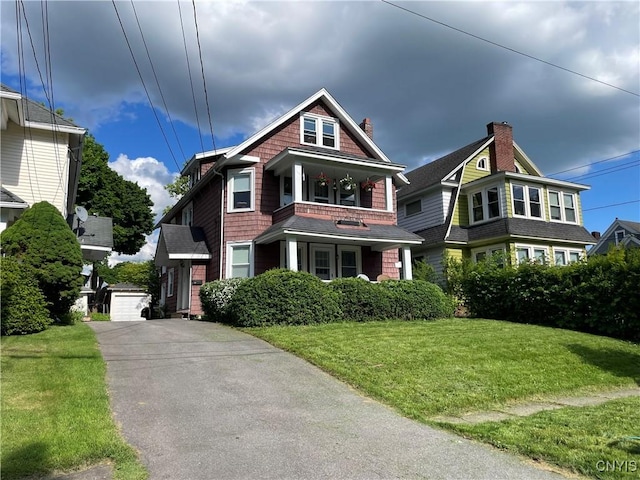 view of front facade featuring an outbuilding, a balcony, a garage, and a front yard