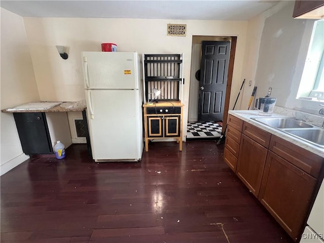 kitchen with sink, white fridge, and dark wood-type flooring