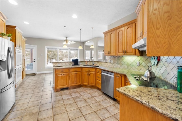 kitchen featuring kitchen peninsula, pendant lighting, decorative backsplash, appliances with stainless steel finishes, and sink