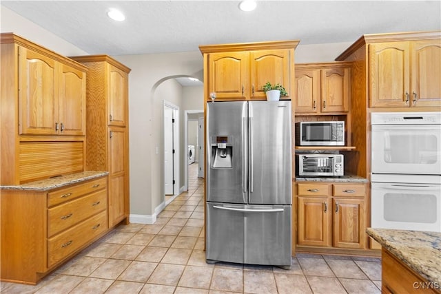 kitchen featuring appliances with stainless steel finishes, light stone countertops, and light tile patterned floors