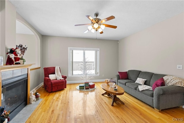 living room featuring a fireplace, light wood-type flooring, and ceiling fan