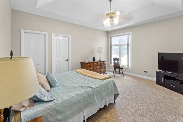 bedroom featuring a raised ceiling, ceiling fan, and carpet