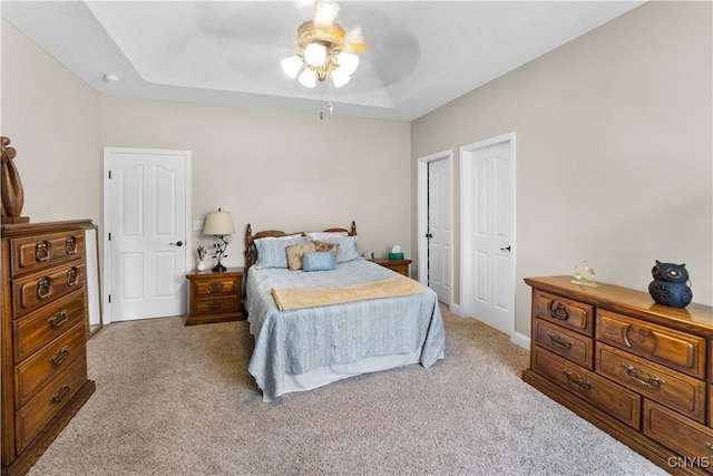 carpeted bedroom featuring ceiling fan and a tray ceiling